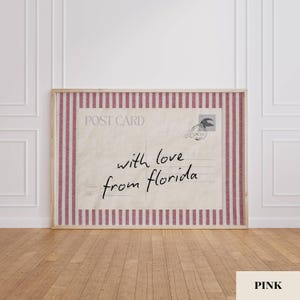 May include: A rectangular framed wall art piece featuring a vintage postcard design with a cream-colored background and dark red vertical stripes. The text reads POST CARD and with love from florida in black script, including a circular postmark.