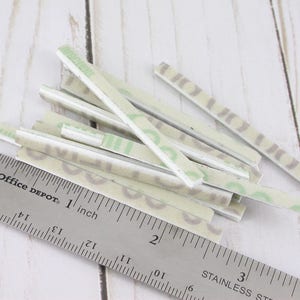 May include: A collection of rectangular, patterned stickers with a ruler that reads "Office DEPOT 1 inch". The stickers have a light green and gray design. The ruler is stainless steel.