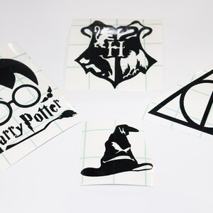 Può includere: Quattro adesivi in ​​vinile bianco e nero con immagini a tema Harry Potter. Gli adesivi includono lo stemma di Hogwarts, il simbolo dei Doni della Morte, gli occhiali e la cicatrice a forma di fulmine di Harry Potter e il Cappello Parlante.