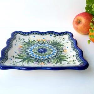May include: A square ceramic serving dish with a blue and white floral design. The dish has a scalloped edge and is decorated with a central floral motif.