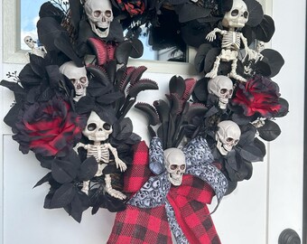 May include: A Halloween wreath featuring black leaves, red roses, and miniature skeleton figures. The wreath is adorned with skull accents and a red and black plaid bow. The overall design creates a spooky and festive atmosphere.