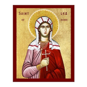 May include: An icon of Saint Lea of Rome, framed in a deep red border. The artwork depicts a woman with a halo, holding a cross. She wears a white headdress and a red and pink robe against a gold background. The text "Saint of Rome" is visible.