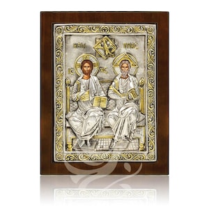Könnte beinhalten: Ein religiöses Icon mit zwei nebeneinander sitzenden Figuren, gerahmt in dunklem Holz. Die Figuren sind in Silber- und Goldtönen gehalten, mit Heiligenscheinen und Büchern. Der Hintergrund ist strukturiertes Silber mit goldenen Akzenten und religiösem Text.