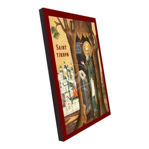 May include: A framed religious icon depicting Saint Tikhon. The image shows a saintly figure with a halo, positioned near a tree, with a church in the background. The frame is a deep red colour, and the text "Saint Tikhon" is visible.