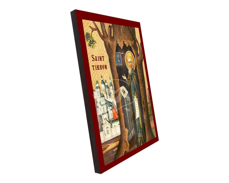 May include: A framed religious icon depicting Saint Tikhon. The image shows a saintly figure with a halo, positioned near a tree, with a church in the background. The frame is a deep red colour, and the text "Saint Tikhon" is visible.