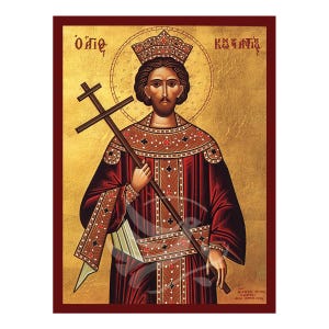 May include: An icon of Saint Constantine the Great, a Byzantine emperor, depicted in a traditional style. He is wearing a red robe with gold trim and a crown. He holds a cross in his right hand. The background is gold with a halo around his head. The text "Ο Άγιος Κωνσταντίνος" is written in Greek at the top of the icon.