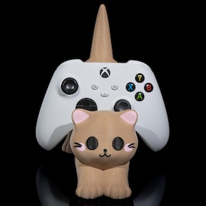 May include: A white Xbox controller stand with a brown cat-shaped base and a white horn on top.