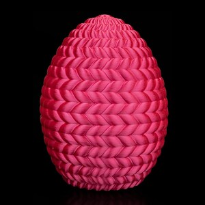 May include: A pink Easter egg made of woven fabric. The egg has a braided pattern and is a decorative item.