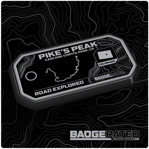 May include: A black and silver rectangular badge with the text "PIKE'S PEAK CASCADE-CHIPITA PARK, CO" and a map outline. The badge also features the Colorado state flag and the words "ROAD EXPLORED". The bottom of the badge reads "BADGERATED.COM".