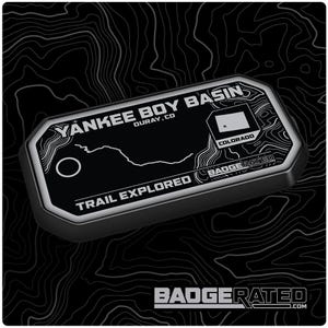 May include: A black and white trail badge with the text "Yankee Boy Basin, Ouray, CO" and "Trail Explored" with a map of the trail and a small Colorado flag. The badge is made by BadgeRated.