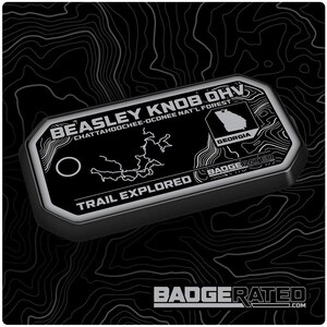 May include: A black and silver rectangular badge with the text "BEASLEY KNOB OHV" and "TRAIL EXPLORED". The badge includes a map of Georgia and the text "CHATTAHOOCHEE-OCONEE NAT'L FOREST". The bottom of the badge has the text "BADGERATED.COM".