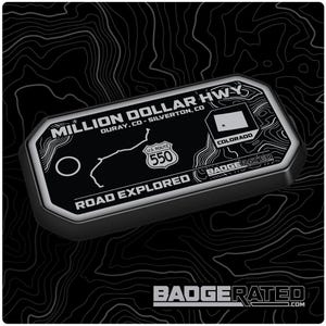 May include: Black and silver metal badge with the text "Million Dollar Hwy" and "Ouray, CO - Silverton, CO". The badge also features a map of the road, a US Route 550 sign, and the text "Road Explored".