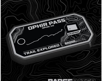 May include: Black and white trail badge with the text "OPHIR PASS OPHIR, CO" and "TRAIL EXPLORED BADGERATED.COM" with a stylized map of the trail and a small white star with the text "COLORADO" below it.