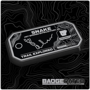 Könnte beinhalten: Schwarzes und weißes Trail-Abzeichen mit dem Text "SNAKE HOT SPRINGS OFFROAD PARK, AR" und "TRAIL EXPLORED". Das Abzeichen zeigt auch eine Karte des Snake-Trails und den Bundesstaat Arkansas mit dem Text "ARKANSAS".