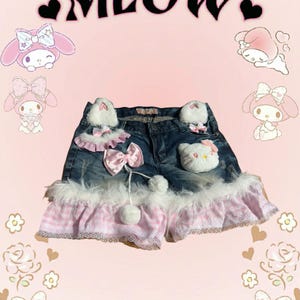 Könnte beinhalten: Blaue Jeans-Shorts mit rosa und weißem Besatz, mit einem weißen flauschigen Besatz, rosa Gingham und einem Hello Kitty-Charakter-Patch.