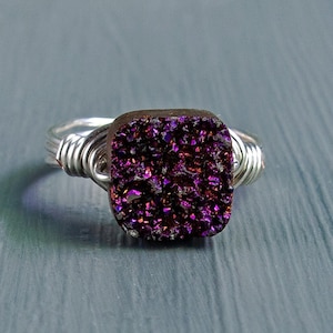May include: A silver wire wrapped ring with a square purple gemstone.