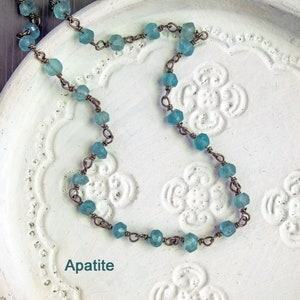 May include: A delicate necklace made with light blue apatite beads and copper wire. The necklace is displayed on a white background with a floral design.