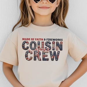 May include: A beige t-shirt with the text "MADE OF FAITH & FIREWORKS COUSIN CREW" in red, white, and blue lettering. The letters have a patriotic design with stars and stripes.