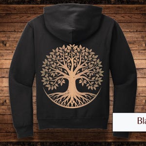 Könnte beinhalten: Schwarzer Kapuzenpullover mit Reißverschluss und einem Baum des Lebens auf der Rückseite. Der Baum ist goldfarben mit einem dunkelbraunen Stamm und Wurzeln.