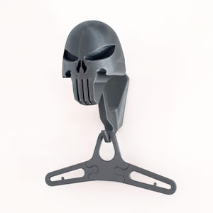 May include: A 3D printed wall hook shaped like the Punisher skull, with a black finish. The hook has a hanger attached to the bottom.