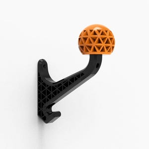 May include: A black wall hook with a geometric orange knob. The hook is made of plastic and has a triangular pattern.