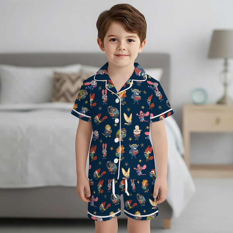 Pu&ograve; includere: Un completo pigiama blu navy per bambini, composto da una camicia a maniche corte con bottoni e pantaloncini abbinati. Il set &egrave; decorato con un colorato motivo di personaggi dei cartoni animati e finiture bianche.