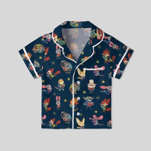 Pu&ograve; includere: Top pigiama blu navy a maniche corte con finiture bianche. La parte superiore &egrave; ricoperta da un motivo di animali dei cartoni animati che leggono libri e stelle gialle. Il top del pigiama ha un'abbottonatura e un colletto.