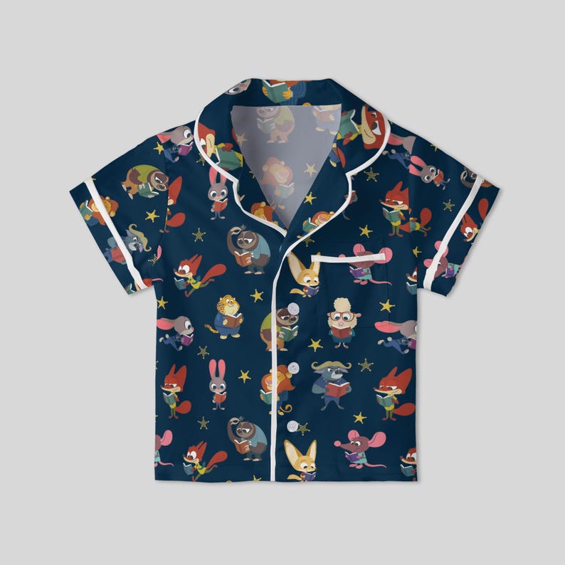 Pu&ograve; includere: Top pigiama blu navy a maniche corte con finiture bianche. La parte superiore &egrave; ricoperta da un motivo di animali dei cartoni animati che leggono libri e stelle gialle. Il top del pigiama ha un'abbottonatura e un colletto.