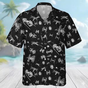 May include: Black short-sleeved shirt with a white space battle pattern. The shirt has a classic collar and a relaxed fit. The design features various starfighters and space stations.