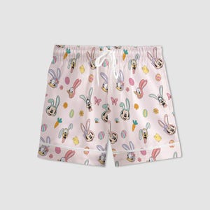 Puede incluir: Pantalones cortos de pijama rosa claro con un estampado repetido de personajes de dibujos animados con orejas de conejo, huevos de Pascua, zanahorias y flores. Los pantalones cortos tienen un cord&oacute;n blanco y ribete blanco.