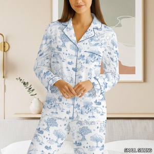 Könnte beinhalten: Weißes Pyjama-Set mit blauem Toile-de-Jouy-Muster mit Zeichentrickfiguren. Das langärmlige Oberteil und die Hose sind mit blauen Paspeln versehen. Der Text "SMALL SIZING" ist unten rechts sichtbar.