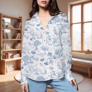 May include: White button-down shirt with a blue Winnie the Pooh pattern. The long-sleeved shirt features a classic collar and a relaxed fit. The pattern includes illustrations of Winnie the Pooh and friends in a whimsical forest scene.
