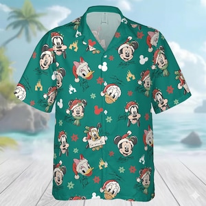 May include: Green button-up shirt featuring a repeating pattern of Mickey Mouse, Minnie Mouse, Donald Duck, and Goofy in Santa hats and scarves. The design includes red stars, Mickey Mouse silhouettes, and castle graphics. The shirt has short sleeves and a classic collar.