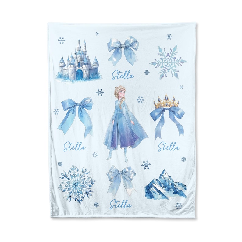 Op de afbeelding: Een lichtblauwe deken met illustraties van een kasteel, sneeuwvlokken, strikken, een berg en een prinses. De naam "Stella" staat in script onder enkele van de afbeeldingen. De deken is wit met een lichtblauw ontwerp.