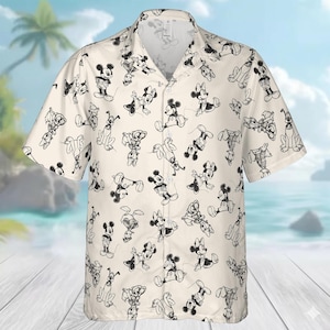 May include: Short-sleeved button-down shirt with a cream background and a repeating black and white cartoon character pattern. The pattern features various poses of Mickey Mouse, Minnie Mouse, and Pluto. The shirt has a classic collar and a relaxed fit.