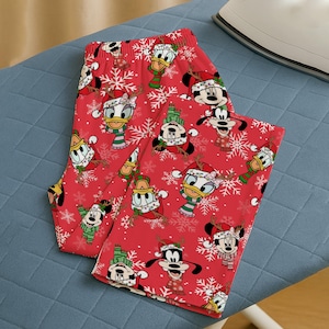 May include: Red Christmas pyjama bottoms with Mickey Mouse, Minnie Mouse, Donald Duck, and Goofy in festive outfits. The bottoms have a repeating pattern of the characters, snowflakes, and holiday accessories.