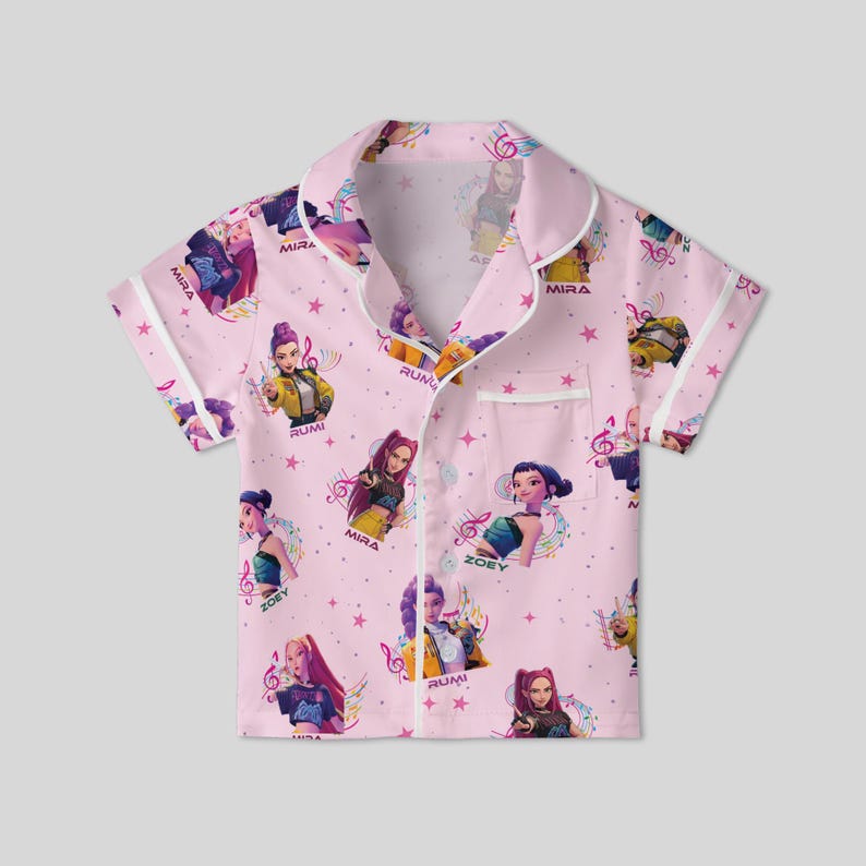 Peut inclure: Haut de pyjama rose &agrave; manches courtes avec un motif r&eacute;p&eacute;t&eacute; de personnages anim&eacute;s, de notes de musique et d'&eacute;toiles. Le haut a une bordure blanche et une poche poitrine. Les noms "MIRA", "RUMI" et "ZOEY" sont imprim&eacute;s.