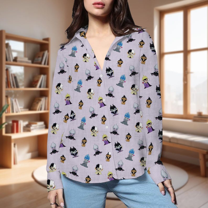 May include: A light purple button-down shirt featuring a repeating pattern of cartoon villain characters in various colors. The long-sleeved shirt is made of a lightweight fabric and is worn open over blue jeans.