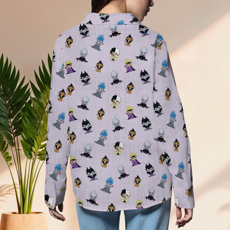May include: A light purple button-down shirt featuring a repeating pattern of cartoon villain characters in various colors. The long-sleeved shirt is made of a lightweight fabric and is worn by a person.