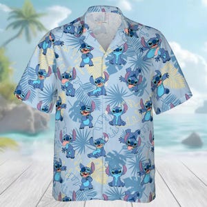 May include: Light blue button-down shirt with a repeating pattern of the character Stitch from Lilo & Stitch. The shirt has short sleeves and a classic collar. The design includes Stitch in various poses, with tropical leaf accents.
