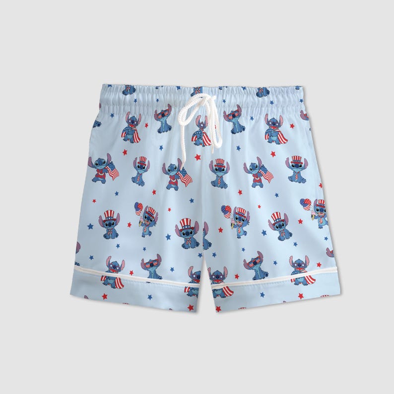 May include: Light blue pajama shorts with a repeating pattern of a blue cartoon character wearing patriotic accessories and holding American flags. The shorts have a white drawstring and white trim.