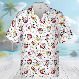 May include: White button-down shirt featuring a repeating pattern of Mickey Mouse, Donald Duck, and Goofy in Santa hats, along with colorful Christmas lights. The shirt has short sleeves and a classic collar, perfect for a festive holiday look.