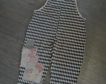 May include: Black and white checkered overalls with a patchwork floral design on the left leg pocket.