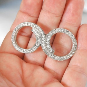 May include: A silver infinity symbol charm with clear rhinestones.