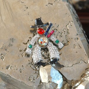 May include: A silver-toned, rhinestone-encrusted clown brooch with a black hat, red nose, and green and blue accents.