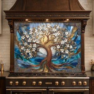 May include: A decorative kitchen backsplash featuring a tree design with white blossoms, brown trunk, and gold accents. The artwork is set against a blue and gold background, framed by a dark brown hood above a black stove.