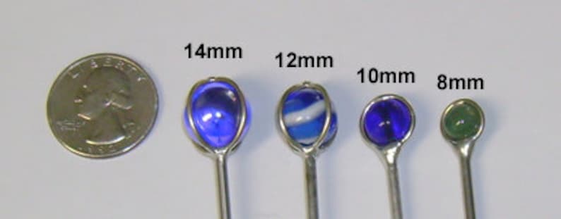 May include: Four glass marbles on silver sticks, with diameters of 14mm, 12mm, 10mm, and 8mm. The marbles are blue, white and blue, blue, and green.