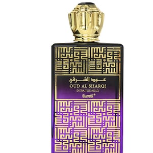 May include: A rectangular perfume bottle with a gold-colored cap and a black and purple body. The bottle features gold Arabic script and the words "OUD AL SHARQI" and "EXTRAIT DE AOUD". The bottle has a gold-colored cap.