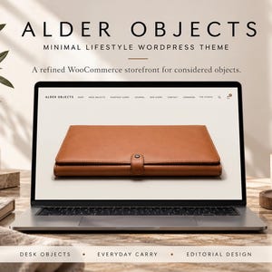May include: A laptop screen displaying a website titled ALDER OBJECTS, featuring a tan leather portfolio with a snap closure. The website navigation includes links for shop, desk objects, everyday carry, journal, our story, contact, and lookbook.