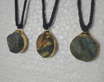 May include: Three necklaces with labradorite stone pendants. The stones are different shapes and sizes, and are set in gold. The necklaces are on black cords.